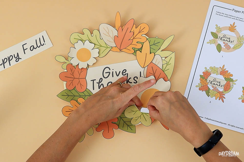 Give Thanks paper plate wreath craft with curled leaves and flower petals for a 3D effect, shown with free printable template for kids.