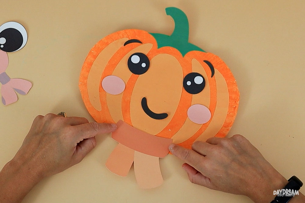 placing a scarf on paper plate pumpkin craft