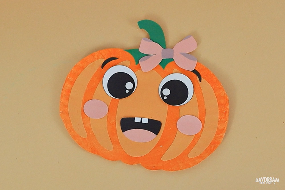 a paper plate pumpkin with a bow on it