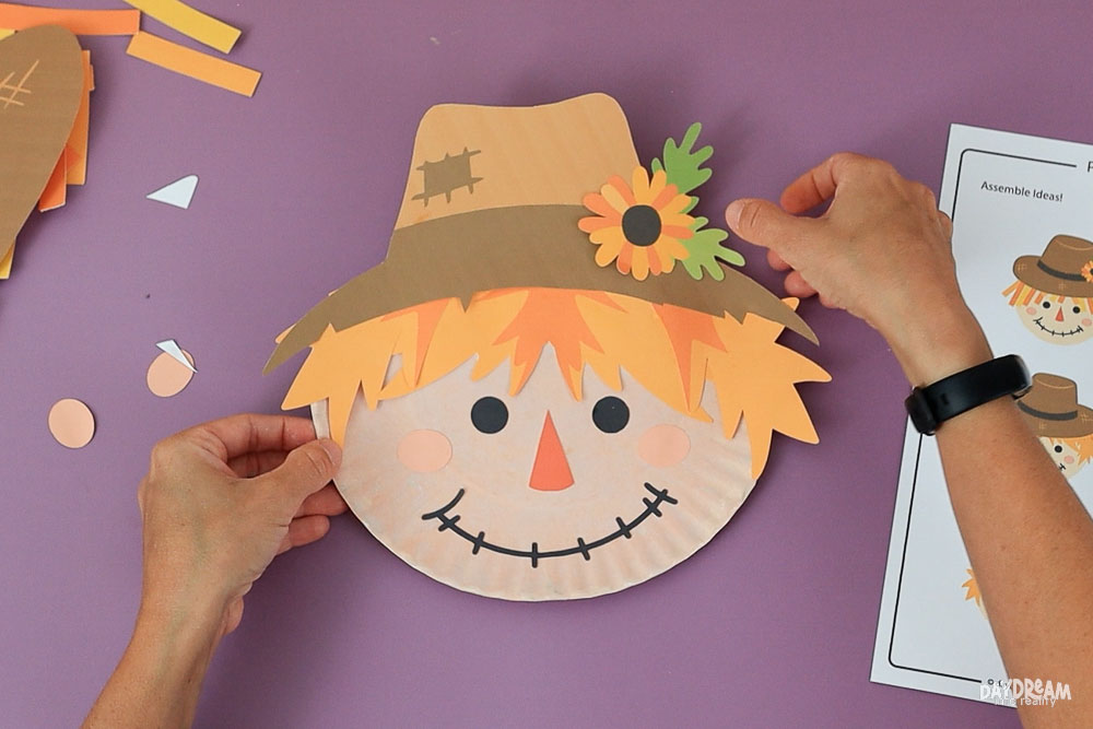 Adding a little floral decoration to paper plate scarecrow