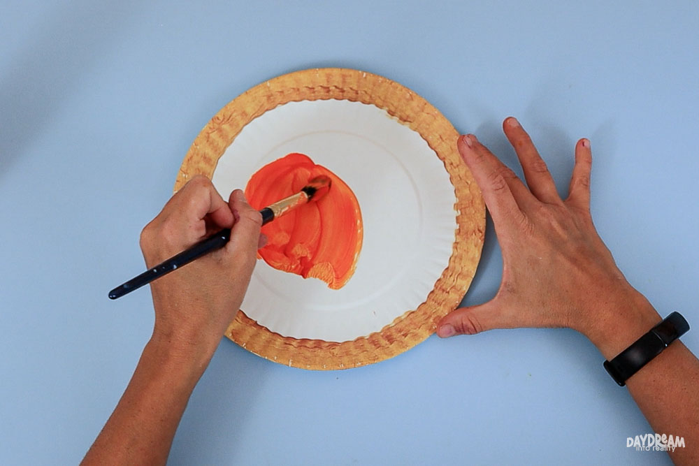 painting paper plate filling with orange to make a pumpkin pie