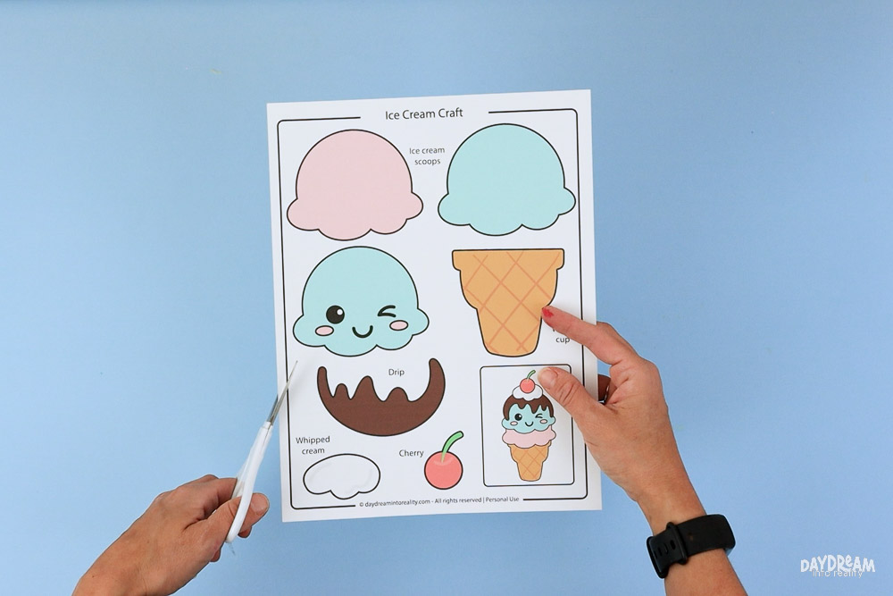 Cutting out the printable ice cream craft template pieces with scissors.