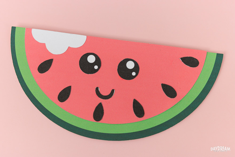 Cute half watermelon slice craft for kids with smiling kawaii face and bite mark detail.